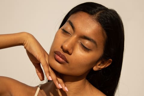 young women with glowy skin and  eyes closed and tilted facing sunlight