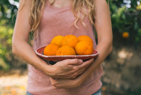 Woman Taking Orange From The Garden