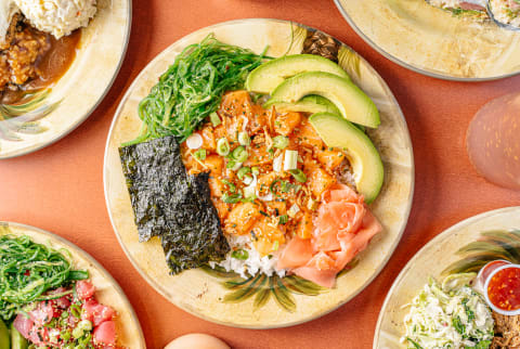 Raw salmon poke bowl with white rice, scallions, seaweed salad, avocado, ginger, and nori