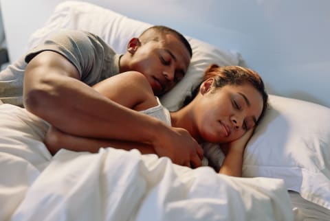 Couple Snuggled Up and Sleeping In Bed