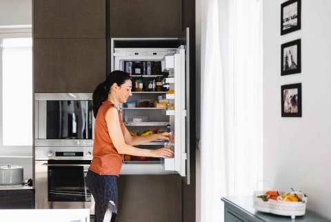 Woman standing in front of open fridge