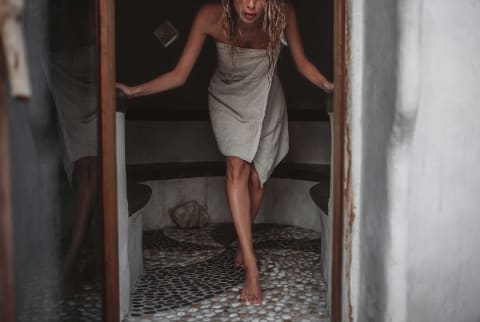 Woman emerges from a sauna wrapped in a towel Woman emerges from a sauna wrapped in a towel