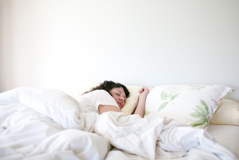 Woman Sleeping in white bedroom with plants on pillow