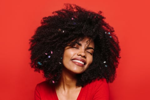 woman with an afro and glitter on a red background