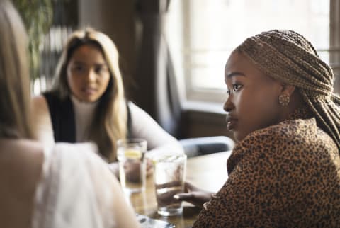 Young woman listening to her friends in a cafe bar