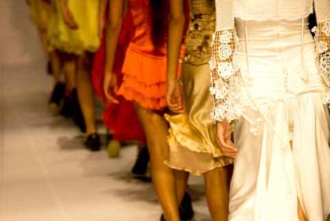 a line of models walking down a high-fashion runway in gowns