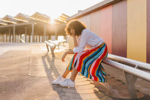 Tired Woman Sitting on a Bench At Sunset