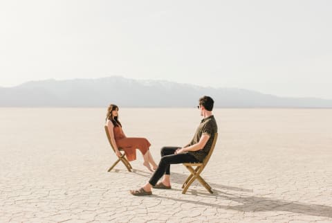 man and woman sitting in desert
