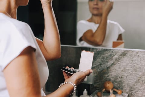 woman applying makeup in mirror
