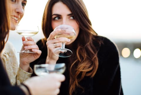 two women holding wine glasses outside