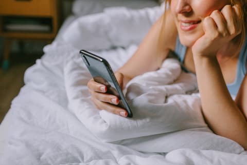 Unrecognizable Woman On Her Bed Looking At Her Phone