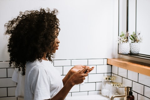 Woman doing skin care in the bathroom in front of a mirror