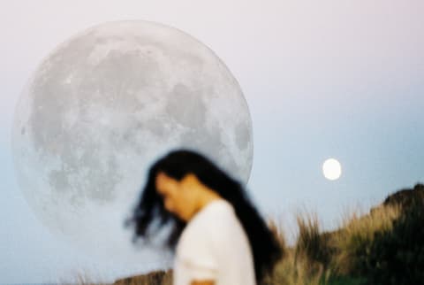 woman on beach with grass and full moon
