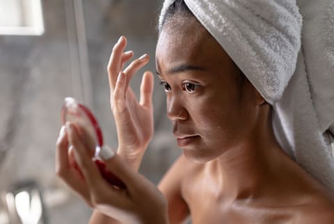 Woman putting on makeup in mirror