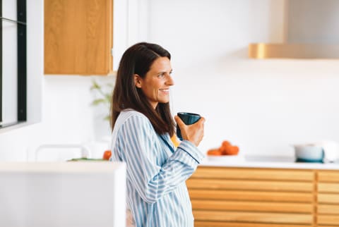 Woman in her 40s drinking coffee in her kitchen