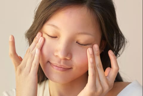 Woman gently massages under eye area with finders