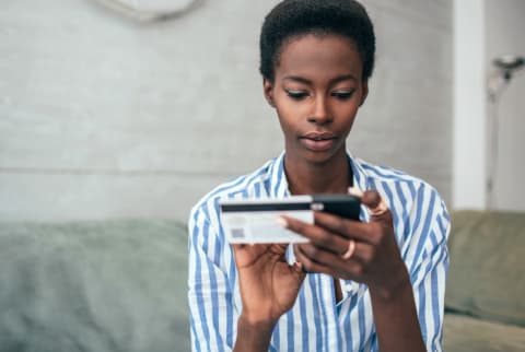 woman using a credit card and her phone