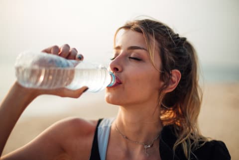 Young woman drinks from a plastic water bottle