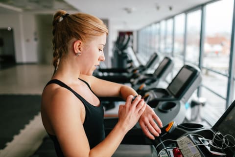 (Last Used: 1/5/21) Woman Checking Her Fitness Tracker at the Gym