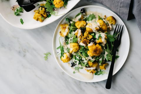 Mediterranean Dish of Turmeric Cauliflower with Tahini Sauce on a Bed of Greens