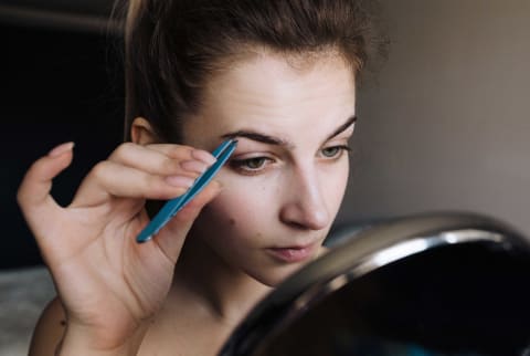 woman plucking eyebrows