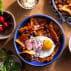 Blue bowl with chilaquilles with eggs and radishes