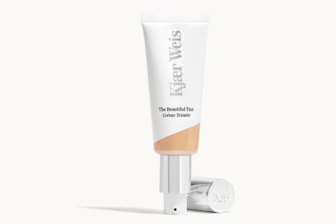 Kjaer Weis Tinted moisturizer in bottle with cap next to it