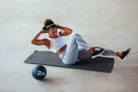 woman working out doing crunches on yoga mat