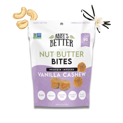 Purple and white packed food item with cartoon cashews and a vanilla flower on each corner. The bites of food are cream colored vanilla cashew nut butter snacks. 
