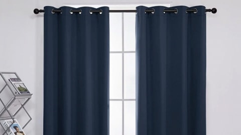two blackout curtains hanging from window in white room