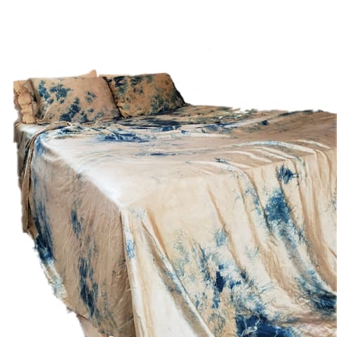 bed made with tie dye silk sheets in blue and tan pattern