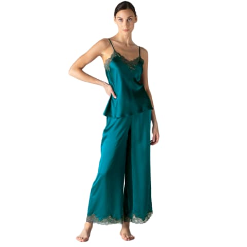Woman wearing teal silk pajama pants and teal silk pajama tank top with her hand on her hip
