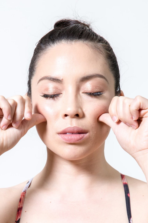 woman pressing thumbs into cheek bones for acupressure woman pressing thumbs into cheek bones for acupressure