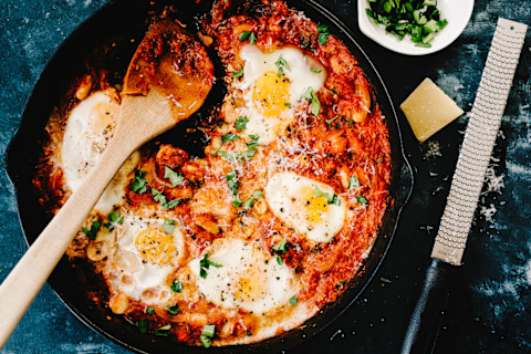 Shakshuka in an iron skillet with parmesan cheese and a cheese grater Shakshuka in an iron skillet with parmesan cheese and a cheese grater