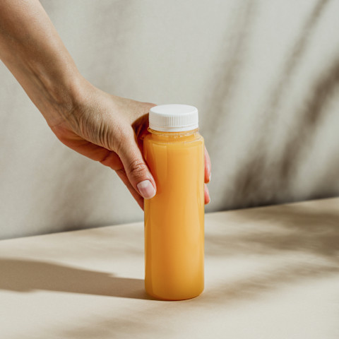 Hand Holding a Bottle of Freshly Squeezed Pineapple, Carrot, and Ginger Tonic Hand Holding a Bottle of Freshly Squeezed Pineapple, Carrot, and Ginger Tonic