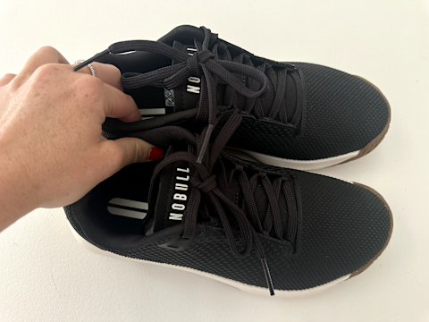 nobull sneakers held against white background