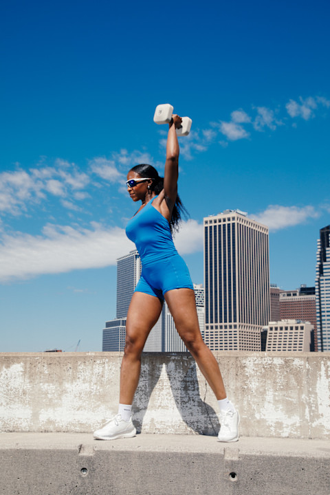 woman outside blue set lifting weights urban skyline woman outside blue set lifting weights urban skyline