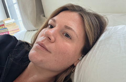 tester wearing earbuds laying on bed sideways