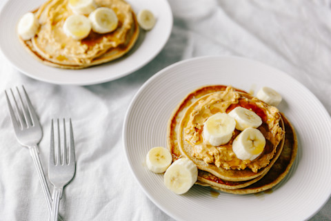 Two Plates Of Vegan Pancakes With Peanut And Banana Two Plates Of Vegan Pancakes With Peanut And Banana
