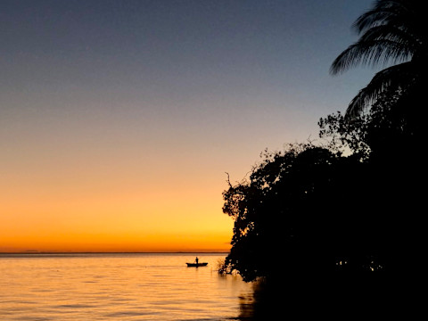 man in small boat rowing at sunset man in small boat rowing at sunset
