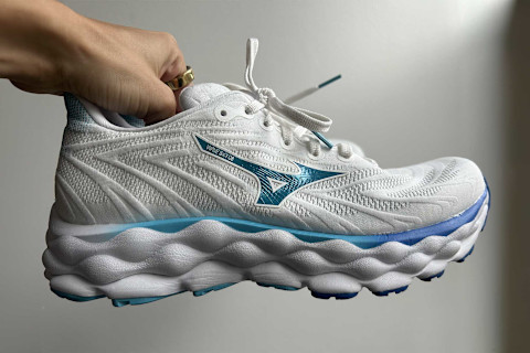 writer's hand holding up the mizuno wave sky running shoes