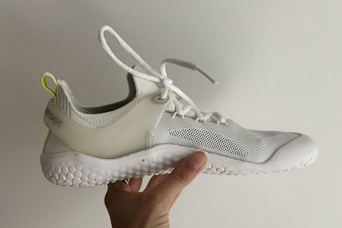 writer's hand holding up the Vivobarefoot Motus Strength shoes