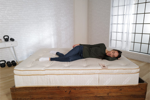 mindbodygreen tester laying on side on saatva latex hybrid