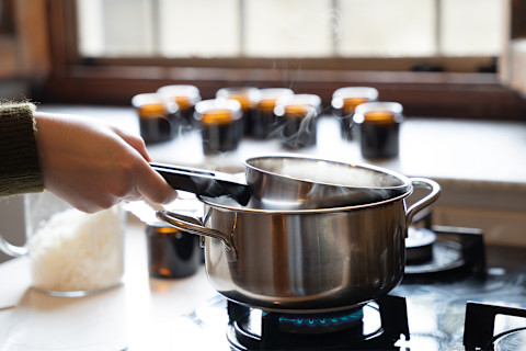 Woman heating wax over a saucepan to make candles Woman heating wax over a saucepan to make candles