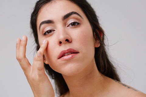 Young Woman Applying Eye Cream to Undereye Young Woman Applying Eye Cream to Undereye