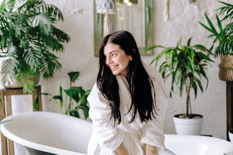 Smiling Woman In A Bathrobe Sitting In Her Bathroom Smiling Woman In A Bathrobe Sitting In Her Bathroom