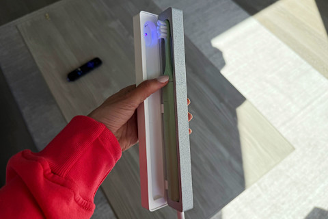 photo of SURI toothbrush in UV cleaning case in writer's hand