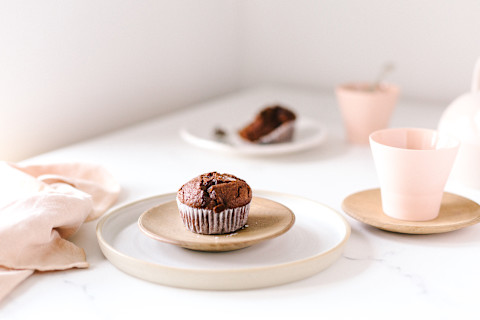 Chocolate muffin on wood plate and white ceramic plate with fork on a table sprinkled with sea salt and accompanied with tea Chocolate muffin on wood plate and white ceramic plate with fork on a table sprinkled with sea salt and accompanied with tea