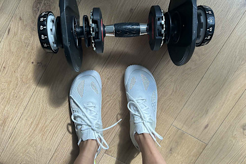 writer's feet in the vivobarefoot motus strength shoes in front of dumbbell