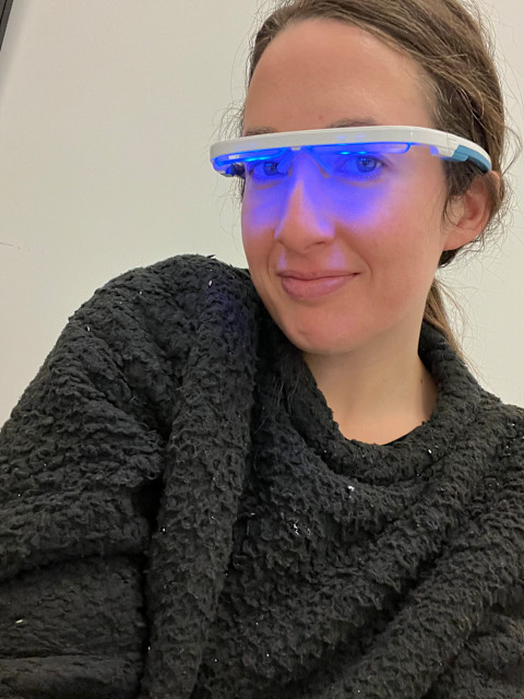 woman in black sweater with blue light emitting glasses over eyes